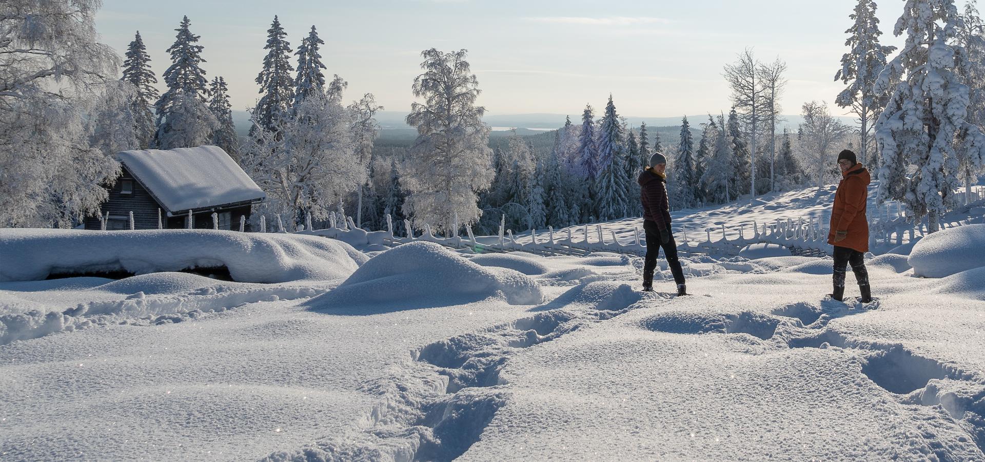 Två personer på snöskor i vintrigt landskap.