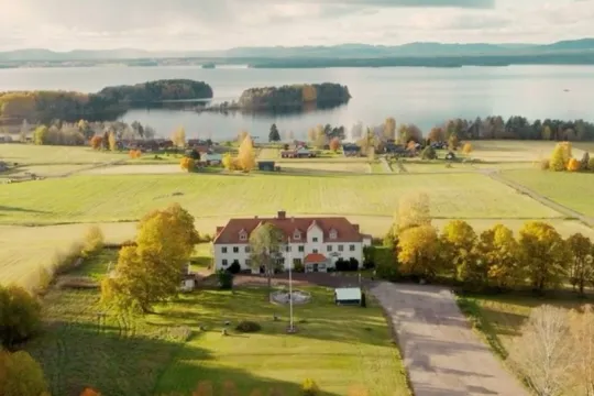 Hotel on fields with a lake in the background in autumn.