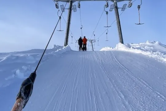 Två personer på väg upp i en skidlift.