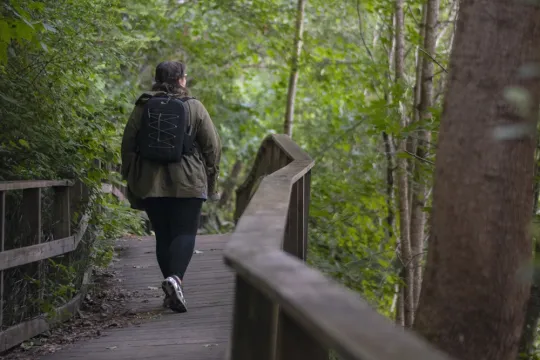 A woman walks on a wooden walkway along the Älvpromenaden in Avesta.