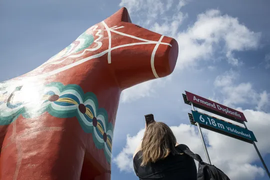 En kvinna fotar en gigantisk dalahäst.