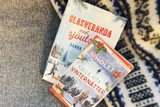 Två pocketböcker ligger på en svart och vit filt.