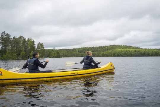 Två personer paddlar en gul kanot sommartid.