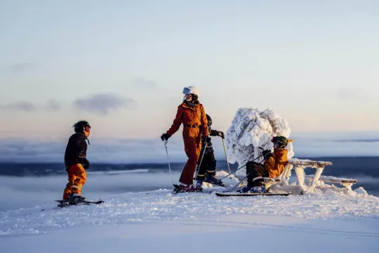 Family on top at the skislope with a clear sky behind them.