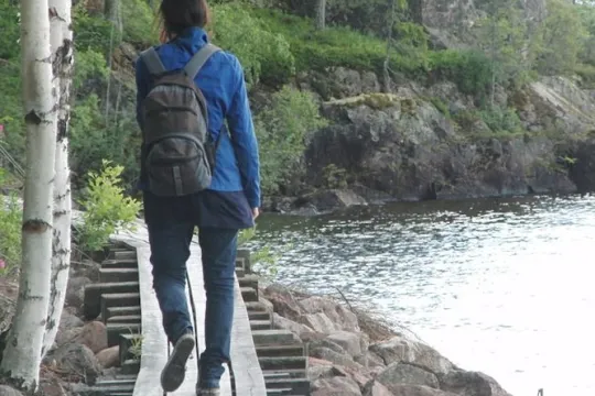 En person som går på en spång längs vattnet.
