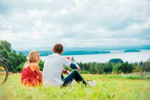 Ett par som sitter på en äng och blickar ut över sjön Siljan.