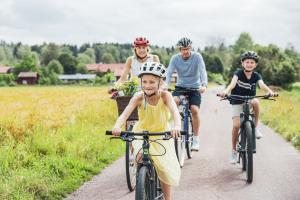 Två vuxna och två barn cyklar i Tällberg i Dalarna.