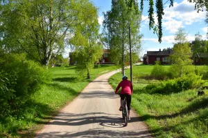 Kvinna som cyklar längs en grusväg.