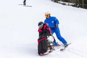 Person i sitski tillsammans med medåkare på funktionell skidskola på Romme Aplin i Borlänge.