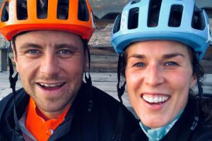 En kvinna och en man iförda cykelhjälmar ler mot kameran.