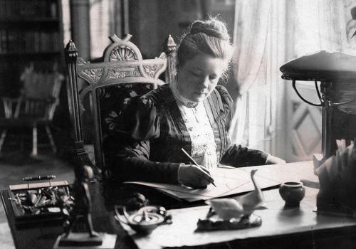 Selma Lagerlöf sitter vid sitt skrivbord och skriver.