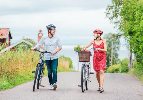 Två personer leder sina cyklar längs väg i Tällberg. 