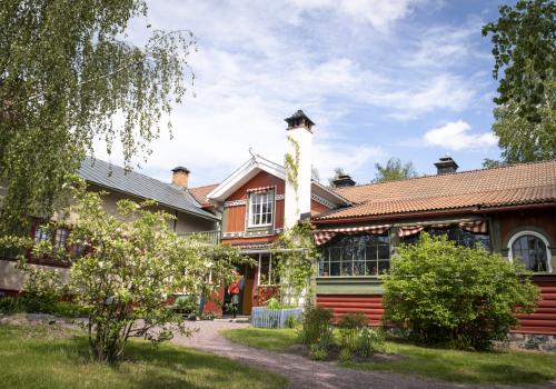 Carl Larsson-gården, ett rött hus med tegeltak och vit skorsten samt grönskande trädgård.