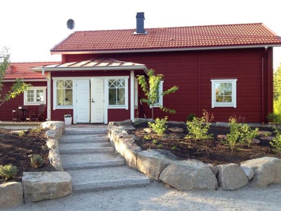  Paved road with steps leading to a red cabin with white door and windows. 