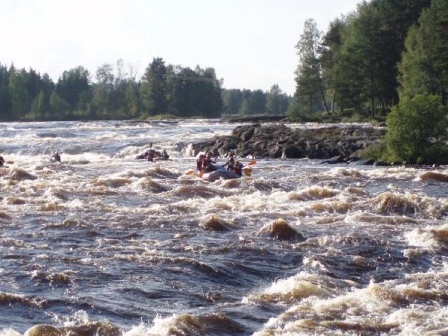 Paddlers in rubber dinghy down wild streams in the river.