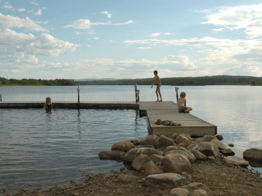 Kids are sitting on a bridge by a lake