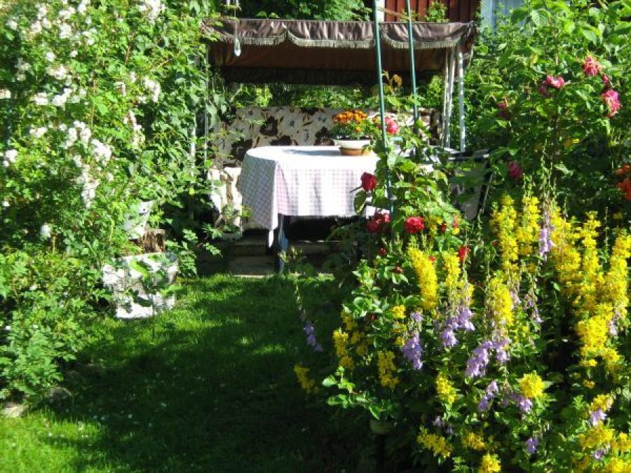 Hammock och bord i en trädgård med blommor.