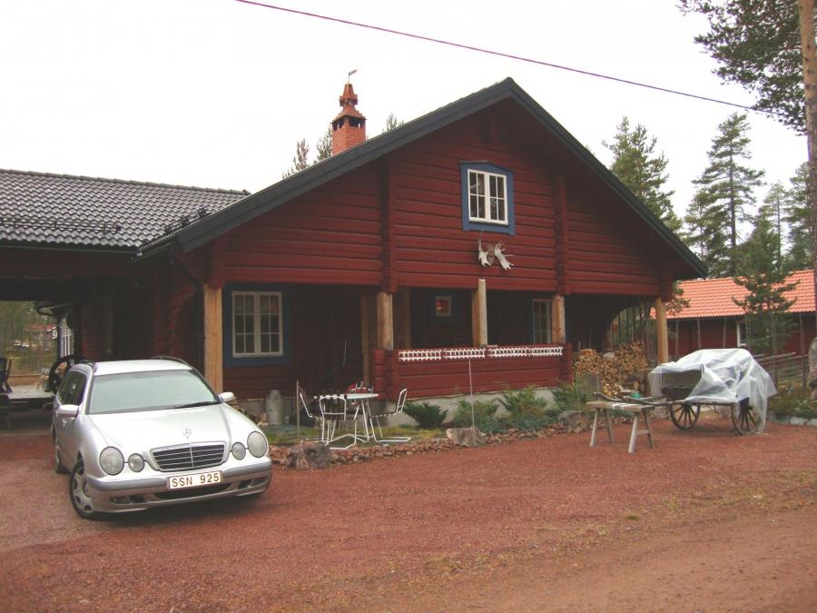 Exteriör av rödmålat hus med stor veranda.