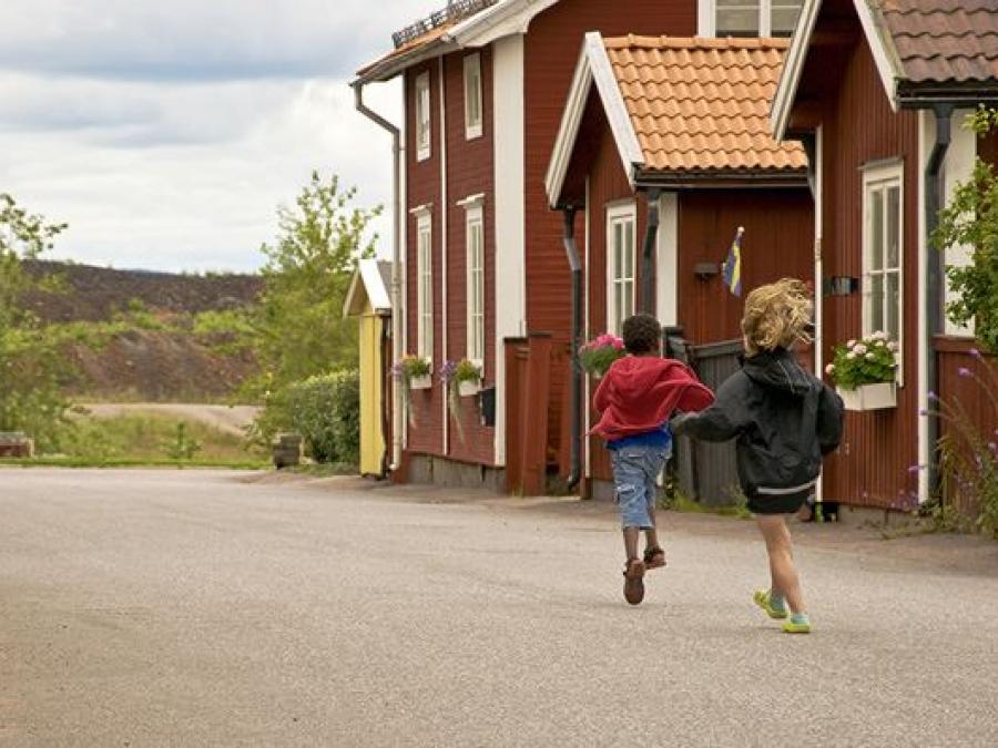 Red older wooden houses, two children playing, slag heaps at the back of the picture.