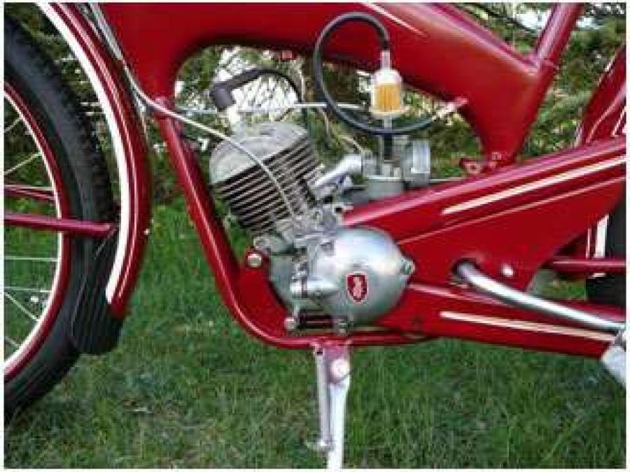 The motor part of a red moped, older model.