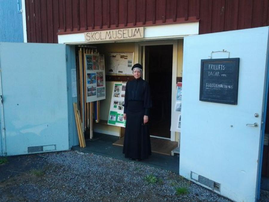 Two white open doors, in the doorway stands a woman in black clothes.