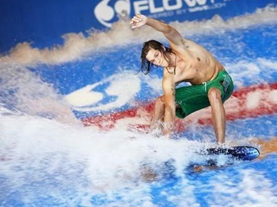 En kille åker på en surfbräda i skummande vatten. 