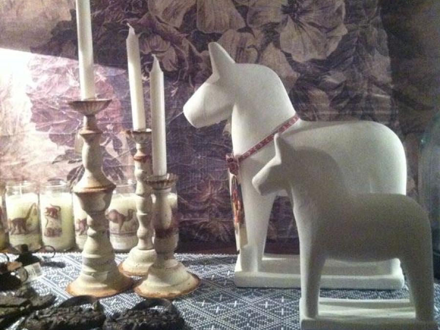 Two white dalahorses in ceramics, three candlesticks, floral pattern in the background.