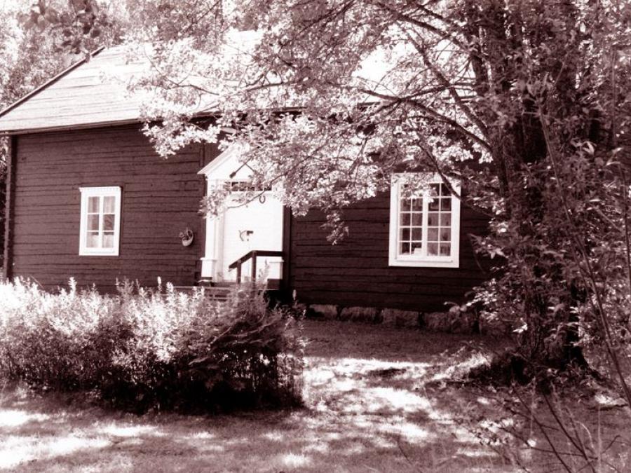 En svartvit bild på ett gammalt timmerhus.