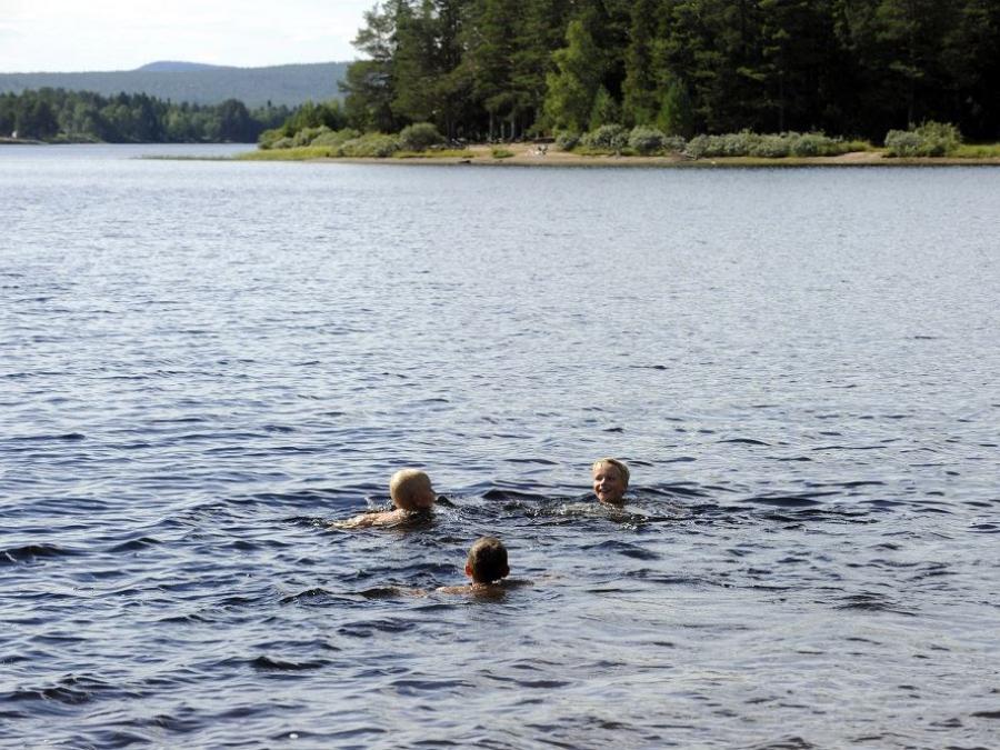 Three persons swimming in a lake