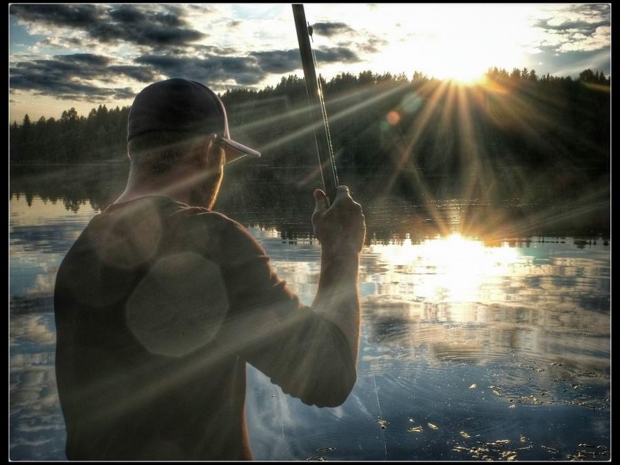 Fiskare med solnedgång som blänker i vattnet.