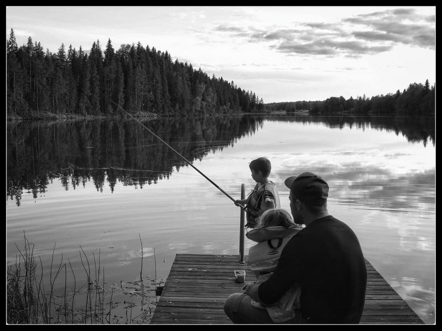 Pappa med två barn som fiskar från brygga.