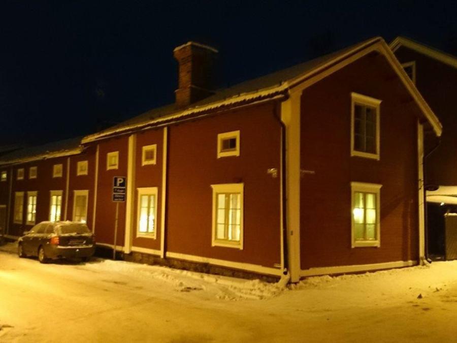 Vinterbild utifrån mot huset ii mörker med lampor som lyser i fönstren.