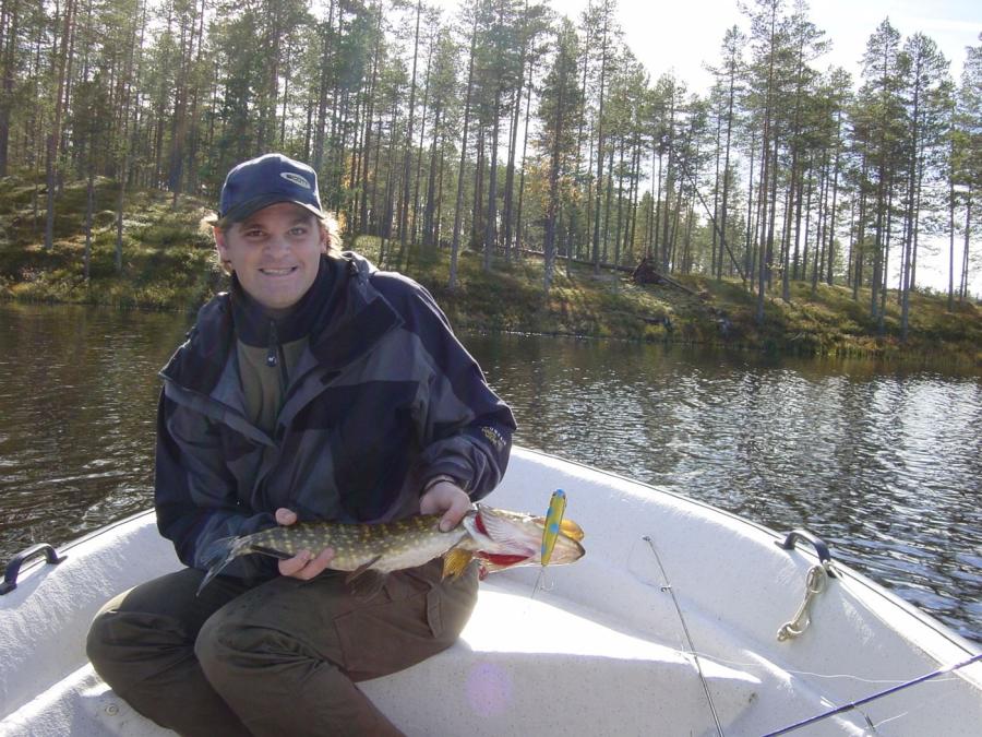 Newly caught pike in the lap of a fisherman sitting in a boat.