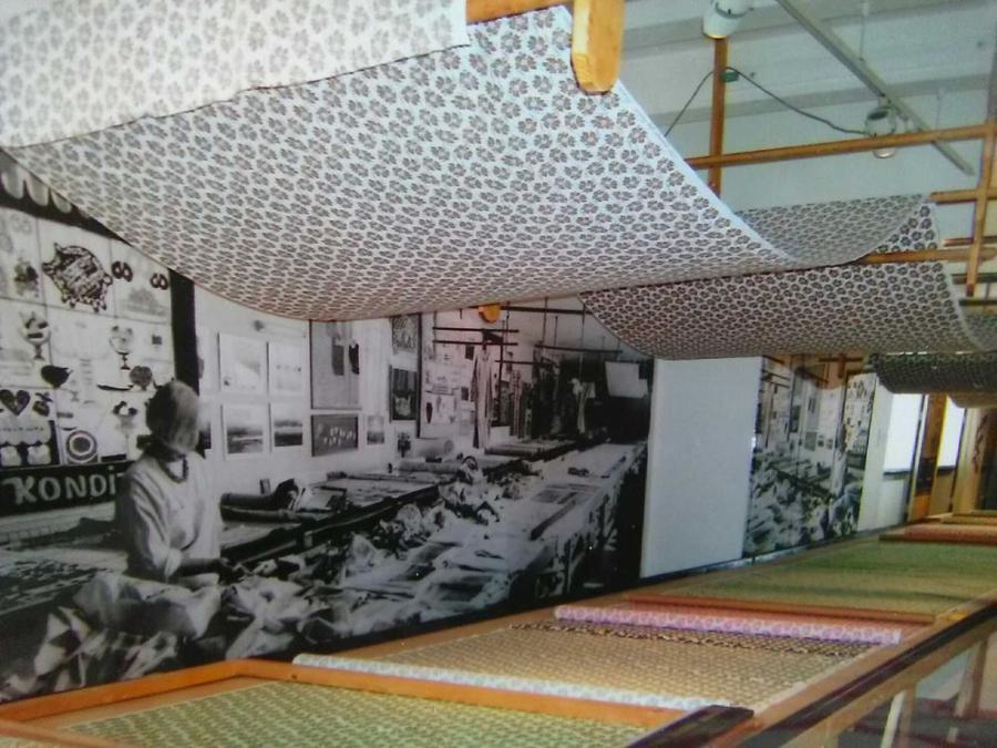 Interiörbild, fotovägg som visar hur det såg ut i ateljén förr i tideed tyger, tyg i taket.n, rader m
