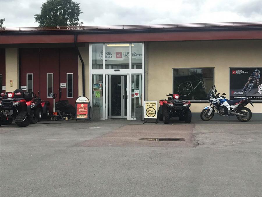asfaltsplan framför Fottas MC med en fyrhjuling och motorcykel bredvid entren. 