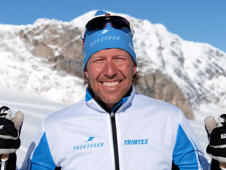 A man in ski clothes with alpine peaks in the background.