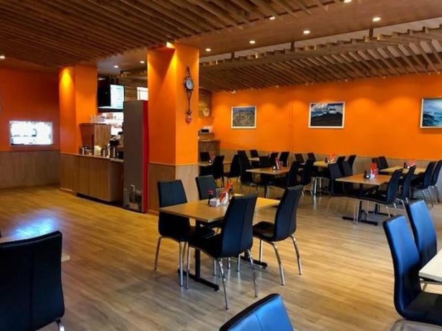 Stolar och bord i restaurangen som har orange väggar.