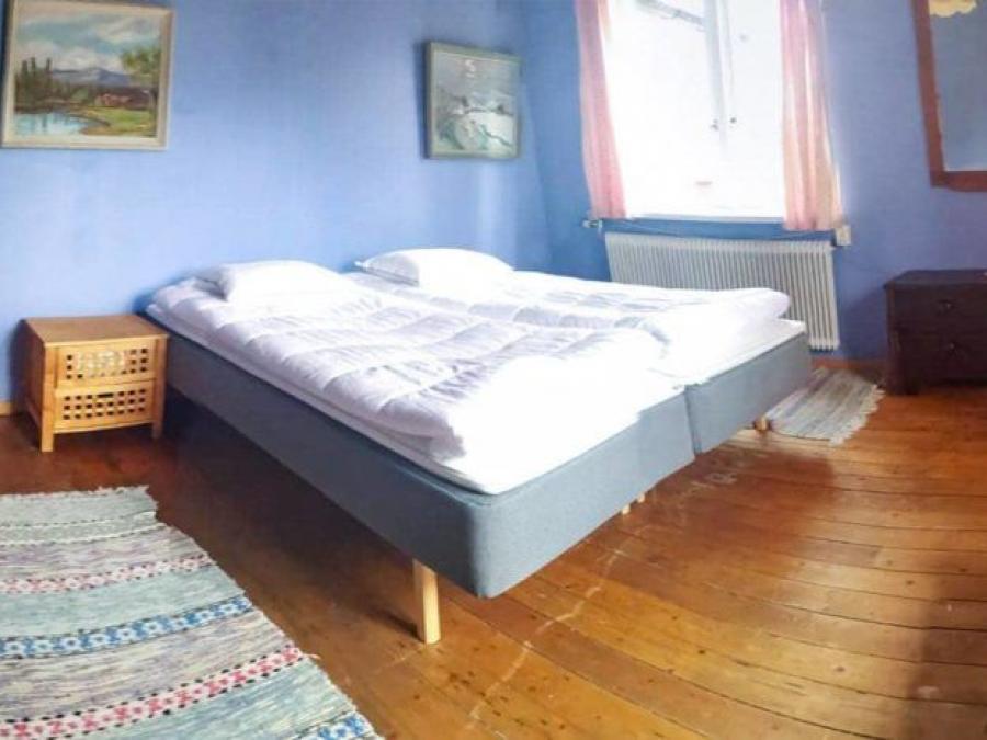 Double bed in a large room with blue walls and a wooden floor.