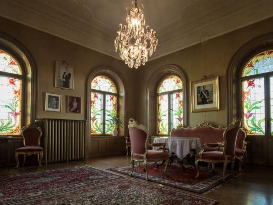 Ett större rum med kristallkrona, fönster med blomstermålningar och möbler i rokoko stil.