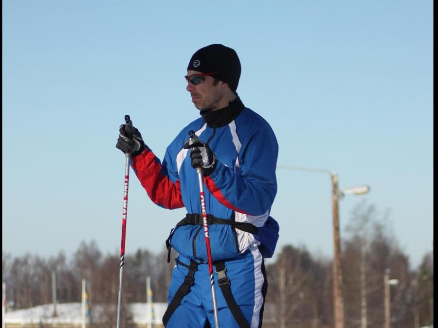 Man in blue ski clothes is ready with skis and ski poles.