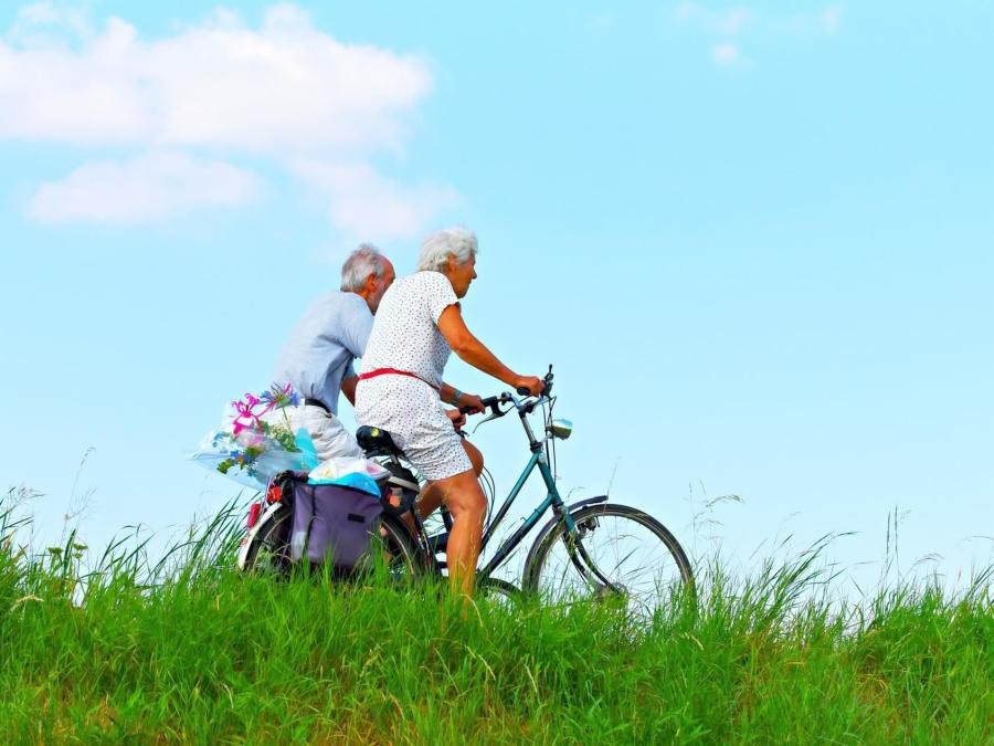 A couple cycling with surrounding grass.