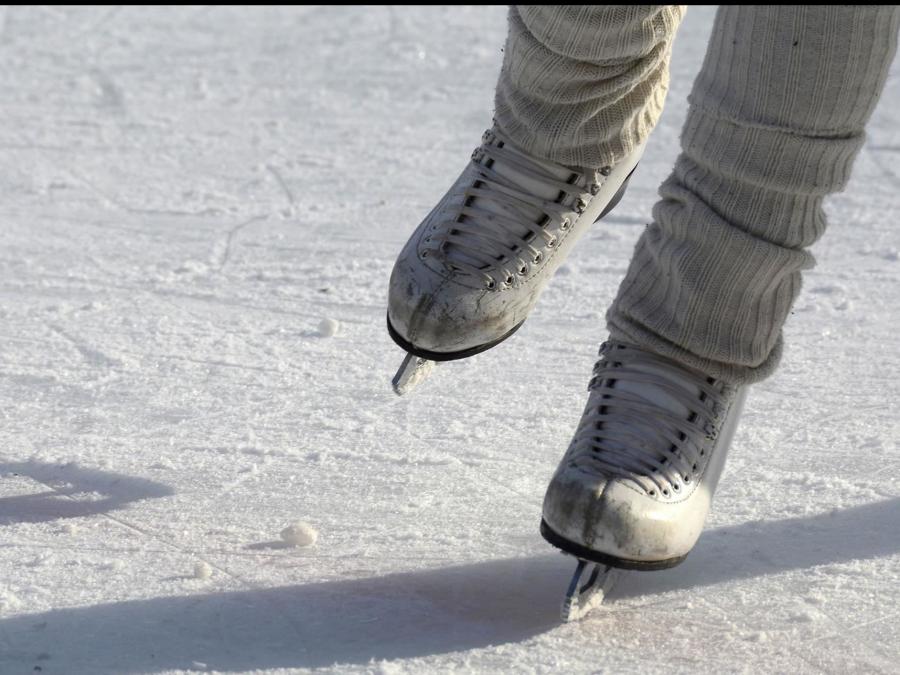 A pair of skates on feet that go on the ice.