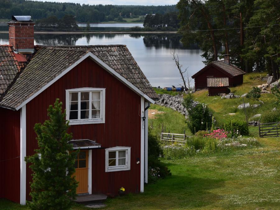 Rödmålat hus med närhet till sjö.