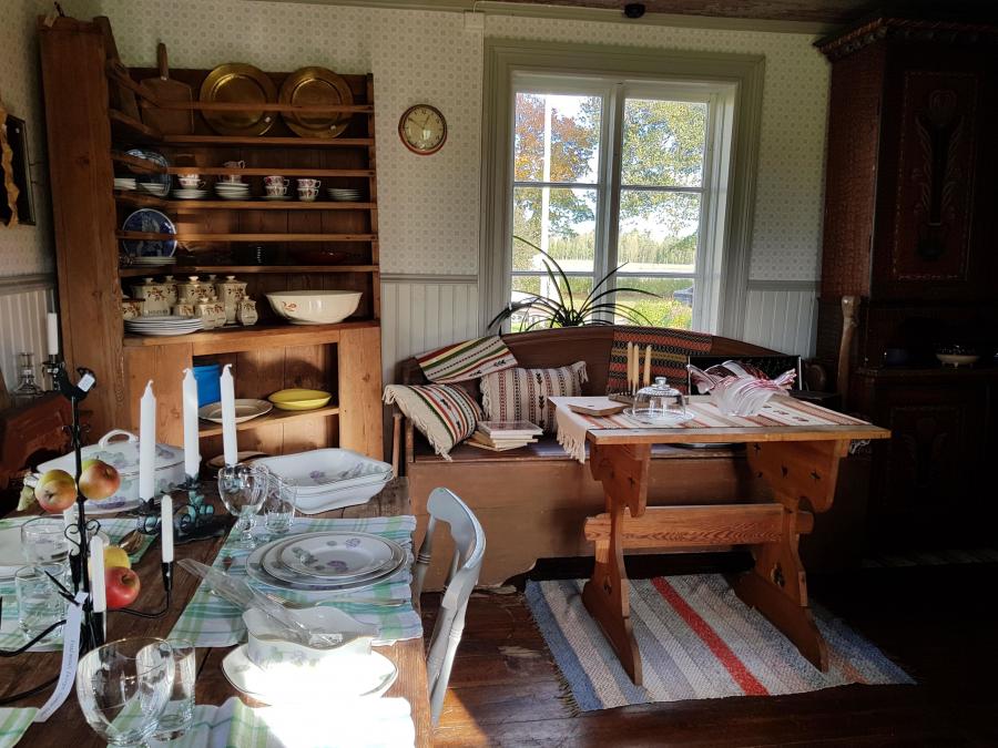 Interiörbild från butiken, ett uppdukat bord, en gammal soffa och ett bord, ett äldre skåp fyllt med produkter.