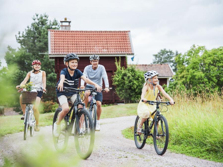Familj som cyklar på en grusväg.