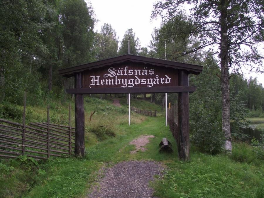 En stig med en träportal med text Säfsnäs Hembygdsgård.