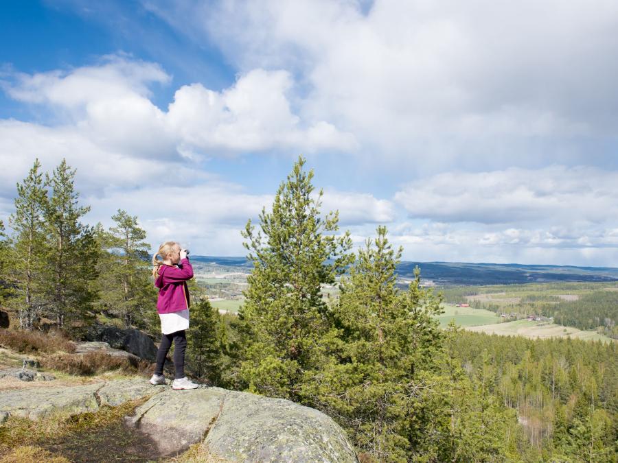 A girl is standing on a mountain viewpoint.
