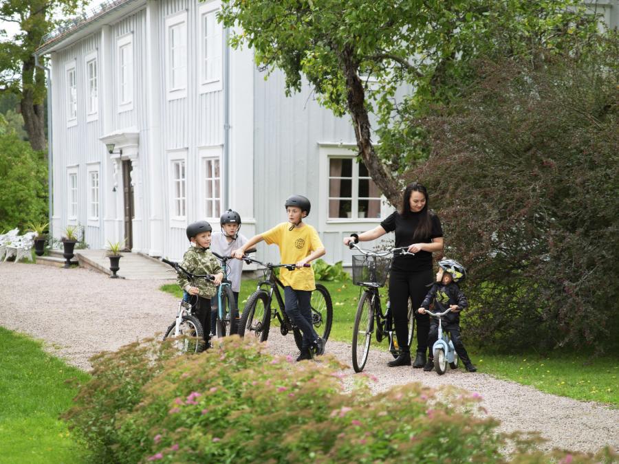 En kvinna och 4 barn som cyklar på en grusväg.