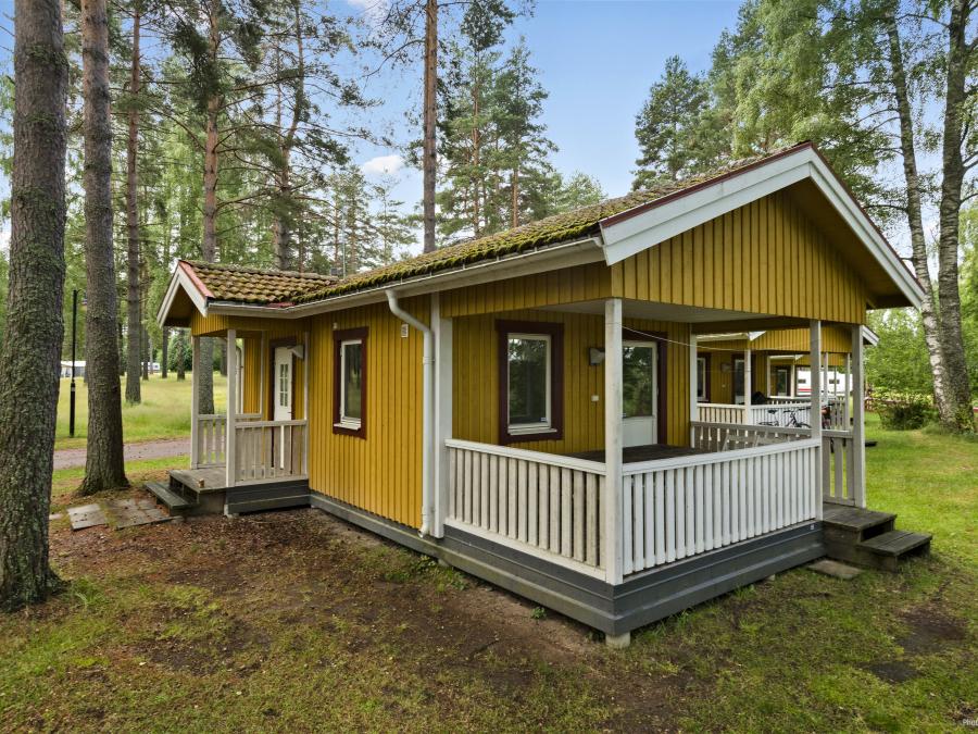 Yellow camping cottage surrounded by trees.