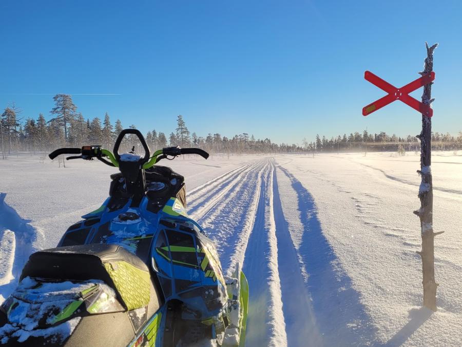 A snowmobile path with a red crossing sign.